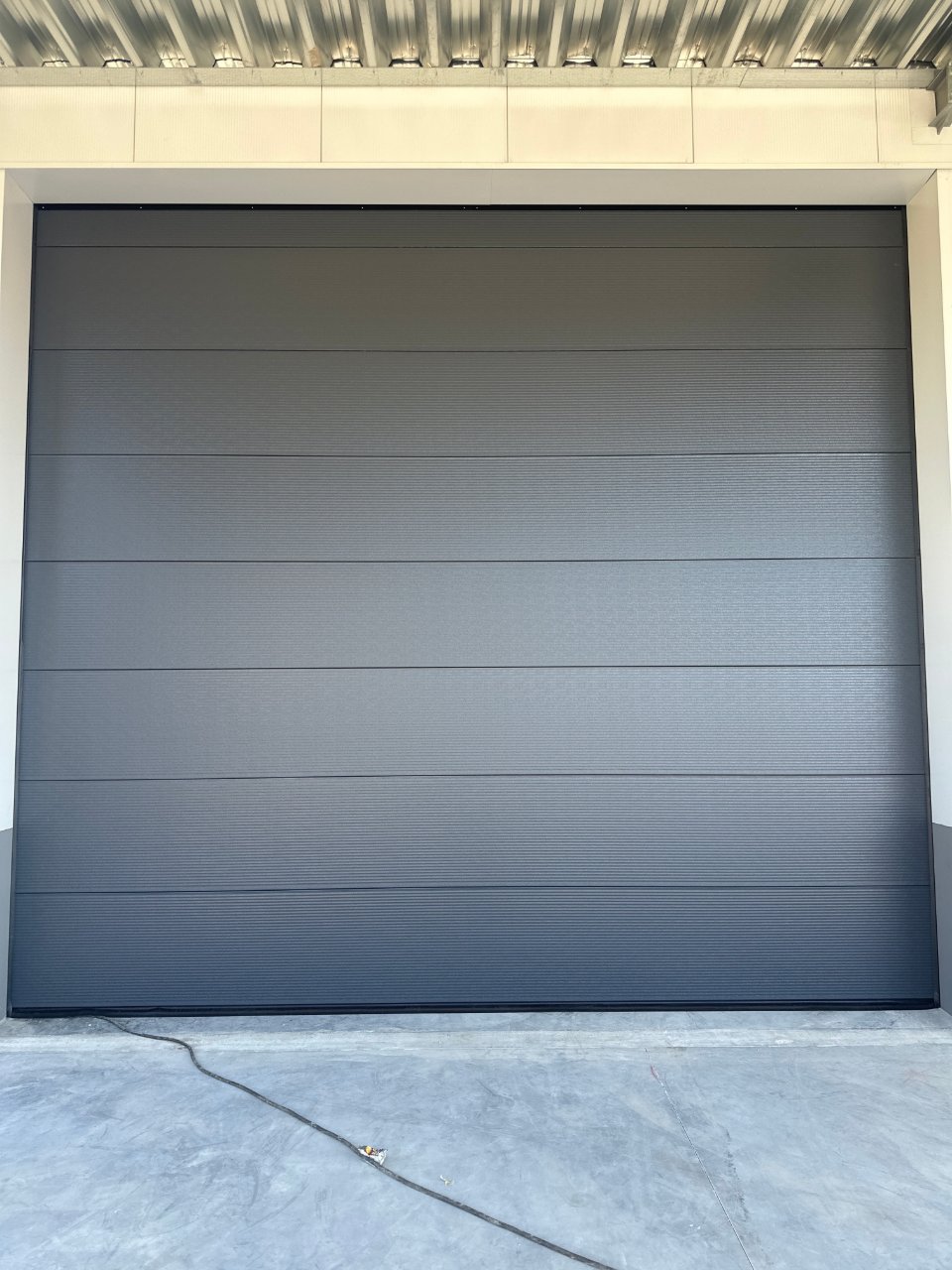 Antraciet sectionale garagepoort met horizontale ribbels, onderhouden door M-Vision